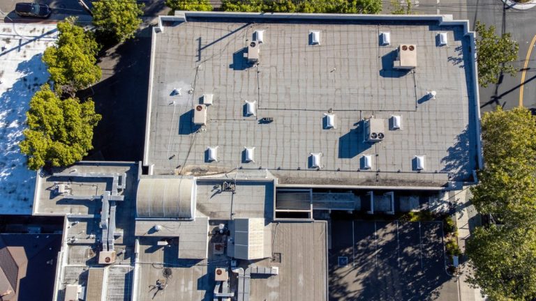 Aerial view of a flat commercial rooftop with air vents and air conditioning HVAC units, in White Bear Lake